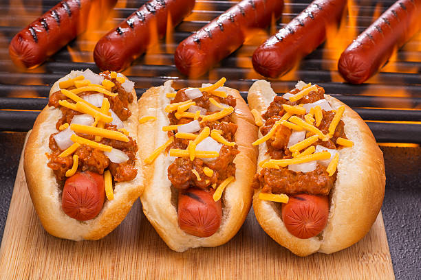 chili hot dogs with cheddar cheese and onions - chili fire stockfoto's en -beelden