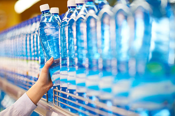 Choosing mineral water Hand taking bottle mineral water from shelf in food store carbonated water photos stock pictures, royalty-free photos & images