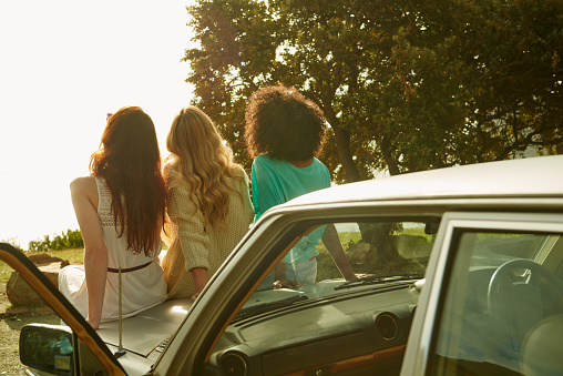 Rearview shot of three young girlfriends sitting on the hood of a car while on a roadtriphttp://195.154.178.81/DATA/istock_collage/a5/shoots/785271.jpg