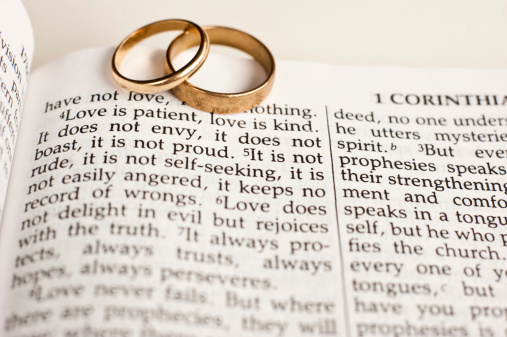 Wedding rings sitting on the 1 Corinthians 13 Bible passage on what love is.