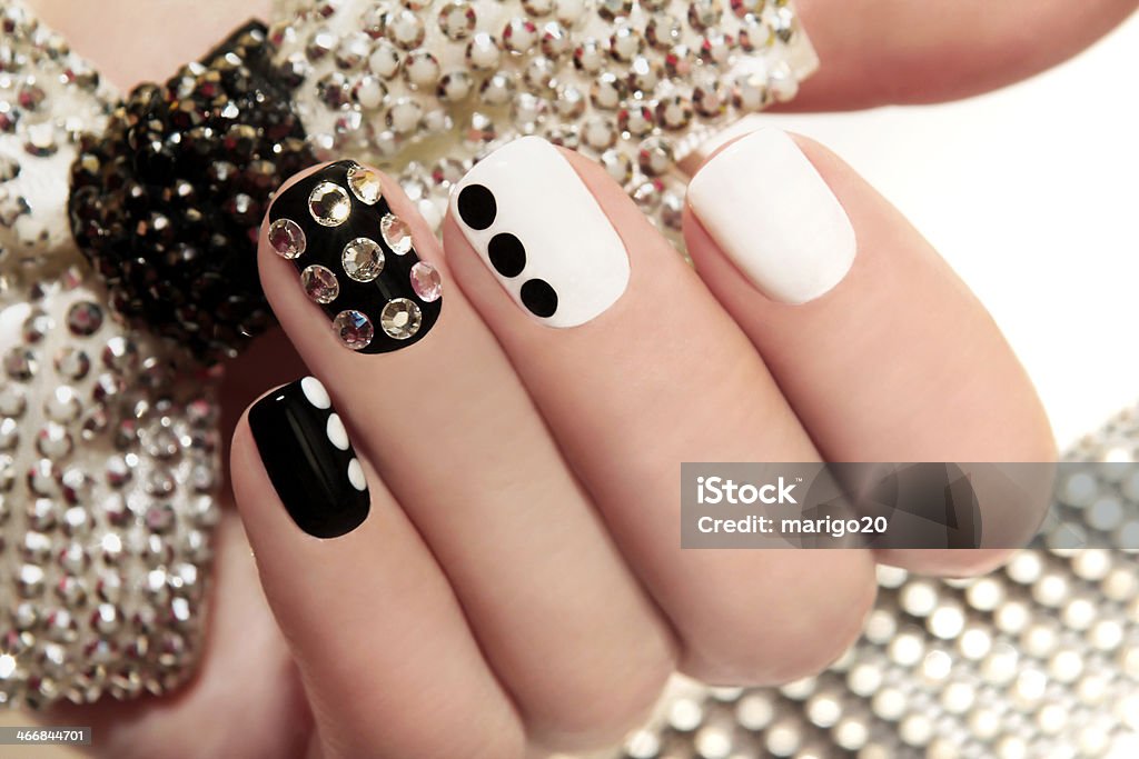 Manicure on short nails. Manicure on short nails covered with black and white lacquered with rhinestones on a black background Artificial Nail Stock Photo