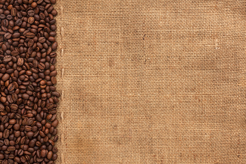 Coffee beans lying on sackcloth, with place for your text