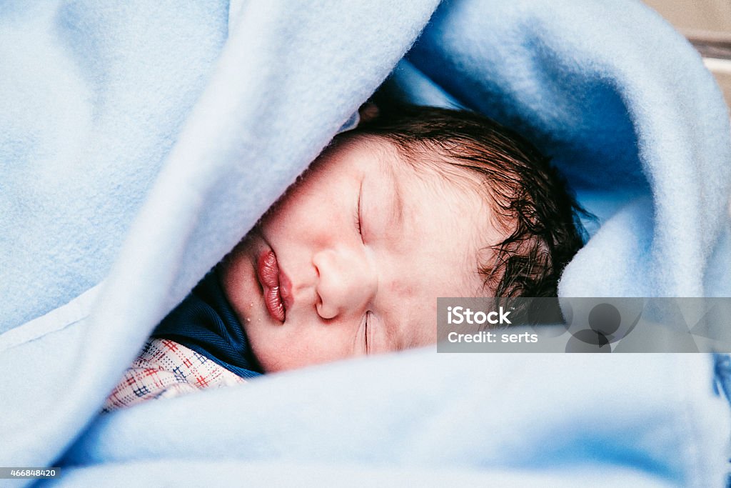 Sleeping newborn baby Close-up portrait of a beautiful sleeping new born sleeping in the blue swaddle at the hospital 0-11 Months Stock Photo