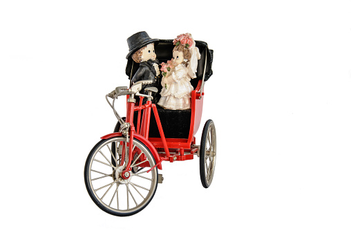 Miniature statue of cute bridal couple and red vintage oriental rickshaw cab, isolated on white
