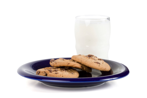 A glass of milk and a plate of chocolate chip cookies isolated on white.  Was this left out for Santa?  Image includes a clipping path.