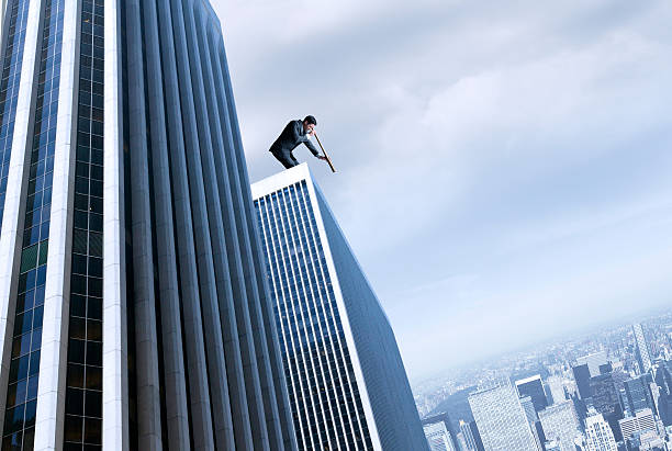 istock Businessman standing on top of skyscraper looking through a spyglass 466859636