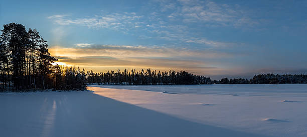 Photo of Panorama of sunrise over snow-covered lake in northern Sweden.