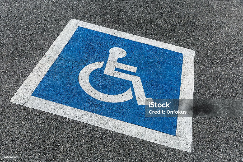 Handicapped Blue and White Parking Sign in Parking Lot Large blue and white handicapped symbol painted on the ground to designate handicapped parking. 2015 Stock Photo