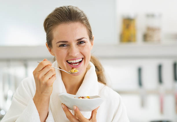 istock smiling young woman in bathrobe having healthy breakfast 466881527