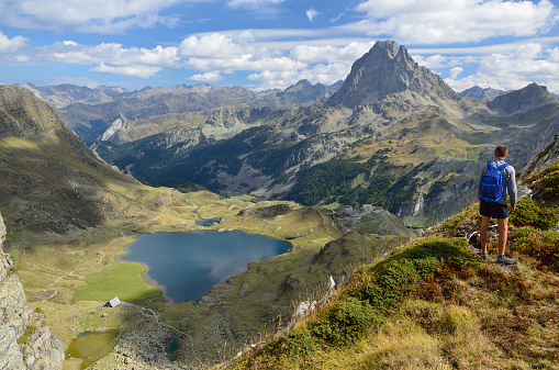 Backpacker with backpack enjoying the turquoise Lago di Sorapiss 1,925m altitude (mountain lake) view as he has mountain walk in Dolomite Mountains, Italy. Active people in nature concept.