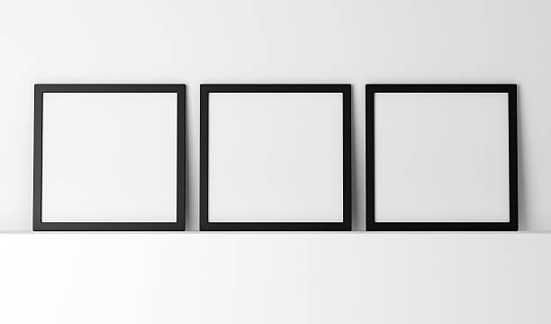 istock Three blank black photo frames in a row on a white shelf 466883654