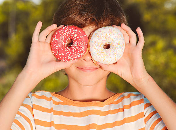 istock Teenager boy having fun with donuts 466884937