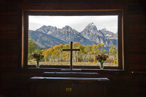 View from Chapel of the Transfiguration The Chapel of the Transfiguration is a historic log church in the Jackson Hole Valley. The chapel was built to frame a view of the Teton Range in a large window behind the altar. The church, which was built in 1925, is now on the National Register of Historic Places. The Chapel of the Transfiguration is at Moose Junction in Grand Teton National Park near Jackson, Wyoming, USA. jeff goulden church stock pictures, royalty-free photos & images