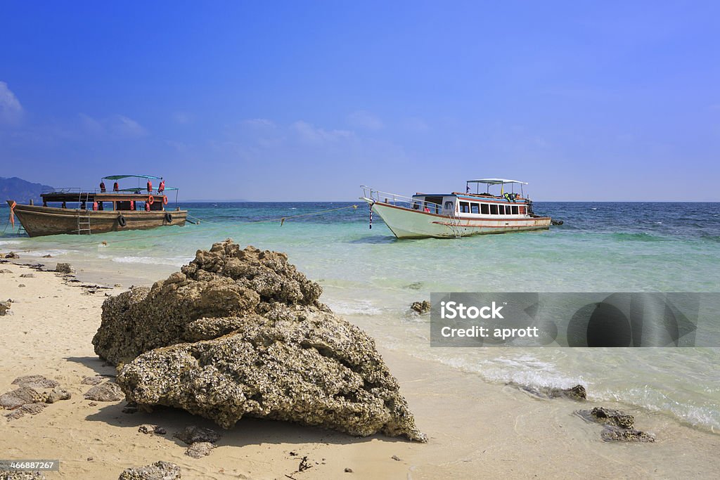 Two boats anchoring at Tup Island, Thailand Two boats anchoring at Tup Island, Thailand. A rock with oyster shells in front. Anchored Stock Photo