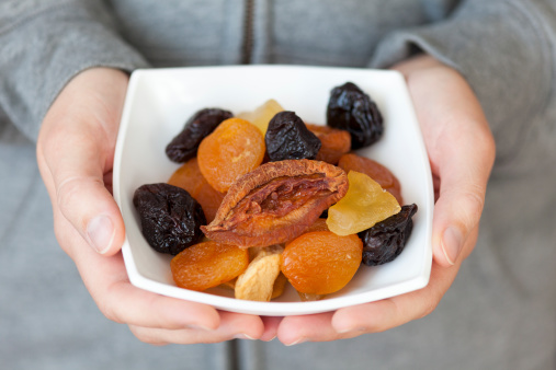 Dried mixed fruits in woman's hands.