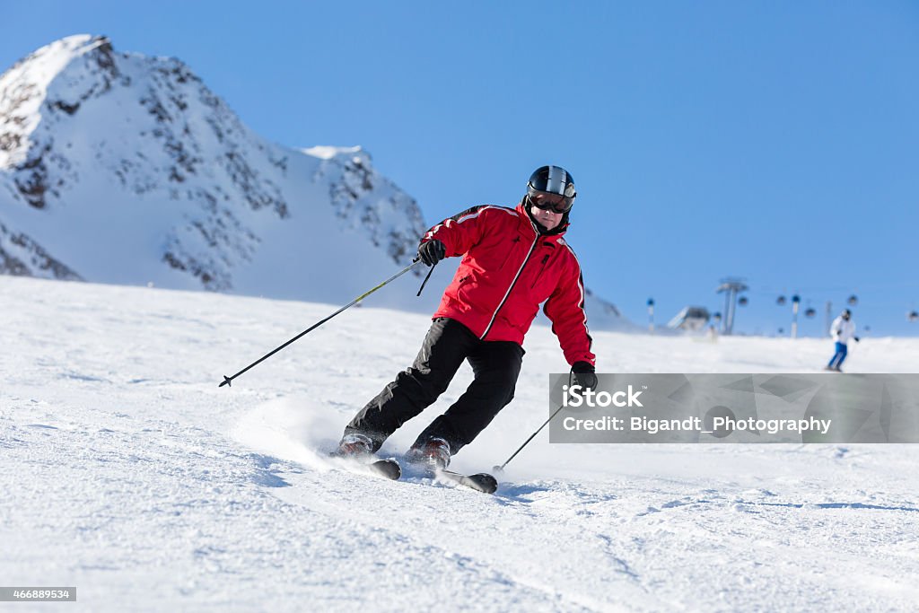 Skier skiing on ski slope Male skier skiing in fresh snow on ski slope on a sunny winter day at the ski resort Soelden in Austria. 2015 Stock Photo