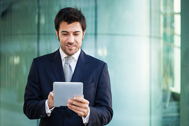 istock A businessman smiling in front of his tablet computer 466901378