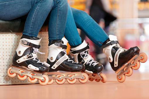 Inline skating. Closeup of two beautiful teen girls showing their rollerblades 