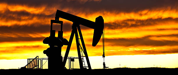 Dramatic Silhouette of Pumpjack in Alberta Oilfield A pumpjack in an Alberta oil field. Horizontal colour image taken near Vulcan. Prairie scenic. The oil industry is a staple Alberta industry and one of the leading segment for jobs in the western Canadian province. The colours in this beautiful sunrise were not enhanced. Panoramic image. Silhouette of oil rig. Crude oil is shipped via the Keystone Pipeline. oil pump oil industry alberta equipment stock pictures, royalty-free photos & images