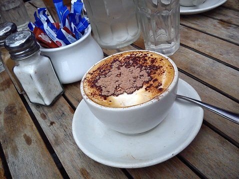 Cup of cappuccino on a wooden table sidewalk cafe