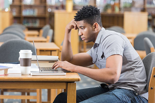 istock Young African American man studying late in college library 466922052