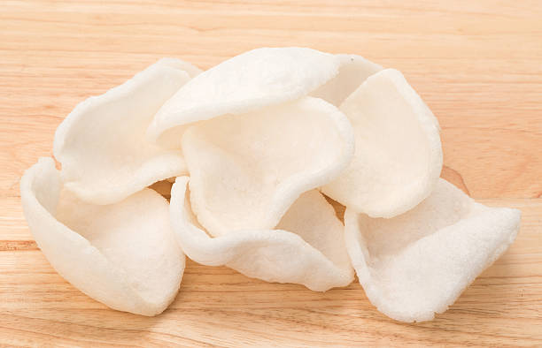 Prawn crackers or shrimp chips Prawn crackers or shrimp chips on a wood surface - studio shot Prawn Crackers stock pictures, royalty-free photos & images