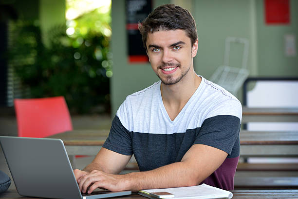 istock Handsome male student sitting and working on a laptop computer 466932118