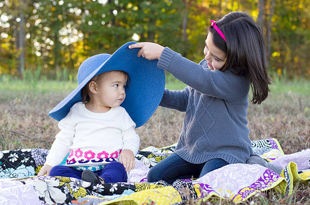 istock Sisters sit together outside playing with a large blue hat 466937645