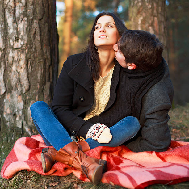 Portrait of young romantic couple sitting in forest stock photo