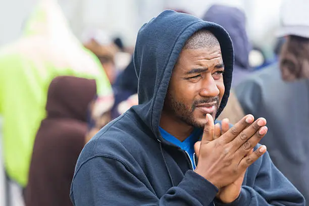 Photo of Man shivering outdoor on crowded sidewalk