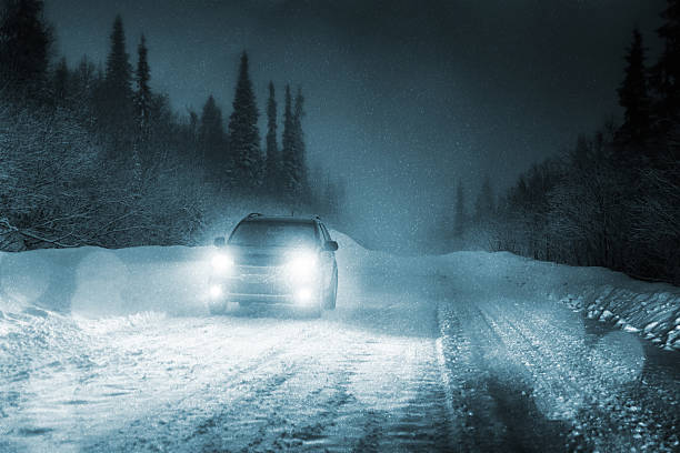 car driving in forest with headlights lighting snowy road - vinter väg bil bildbanksfoton och bilder