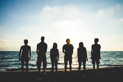 Group of friends standing on the beach at dusk, happiness and relax on vacation.