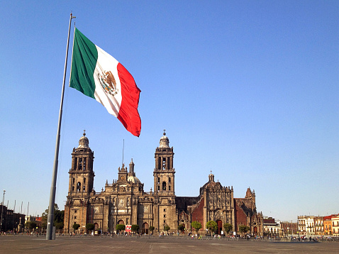 The Plaza de la Constitution, better known as Zocalo, is one of the biggest city squares in the world. It is the centre of Mexico City. A huge flag is in front of the Metropolitan Cathedral (Cathedral Metropolitana). Shot with an iPhone.