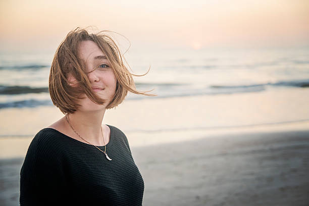 Candid portrait of young woman on the beach at sunset. stock photo