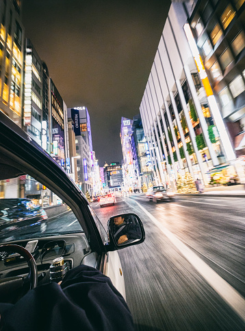 A driver drives a car in the Ginza area of Tokyo, Japan.