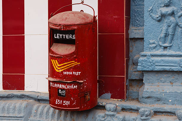 Kanchipuram, India - January 29, 2015: A dusty, old Post Box, belonging to the Indian Postal system, hangs on a temple wall in the South Indian City of Kanchipuram, in Tamil Nadu.  Handpainted on it, are details on where to post the letters, it's location, 'Pillayarpalayam', and the time at which letters will be cleared next: 2.45 pm. The Postal code of the place is also indicated as 631 501. The box is locked. Horizontal format; no people.