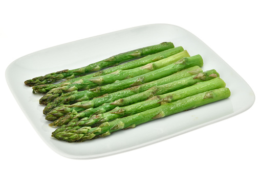 Ready to eat, cooked asparagus on a white plate and a white background