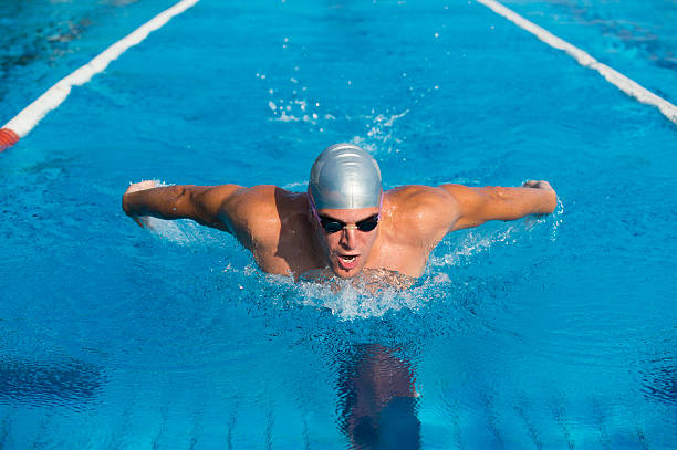 giovane maschio nuotatore professionista a nuoto a farfalla - splashing color image front view head and shoulders foto e immagini stock