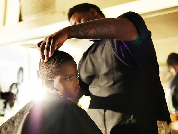 Photo of little boy getting his hair cut in barber shop