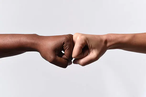 black African American race female hand touching knuckles with white Caucasian woman in agreement partnership and cooperation multiracial diversity immigration concept