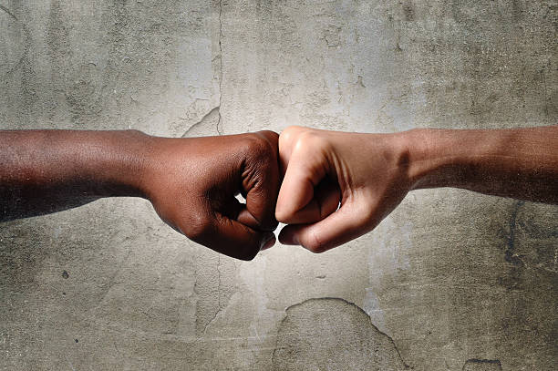 black African American race hand touching knuckles white fist stock photo