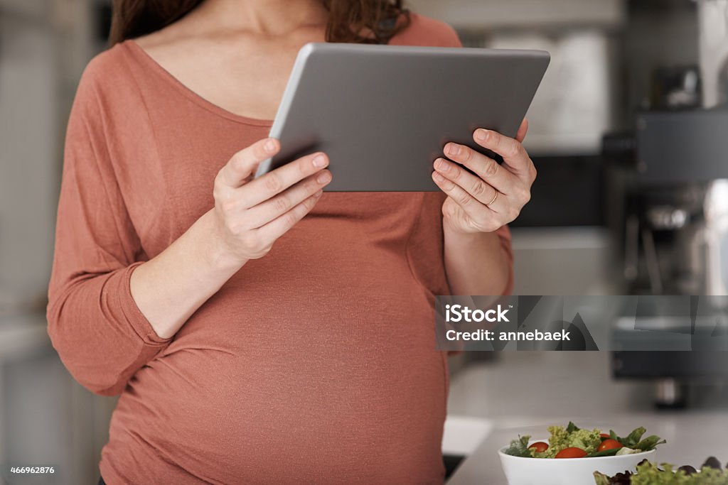 Looking for some pregnancy-safe snacks online Cropped shot of a pregnant woman using her tablet while eating a salad in the kitchenhttp://195.154.178.81/DATA/istock_collage/a9/shoots/785269.jpg 2015 Stock Photo