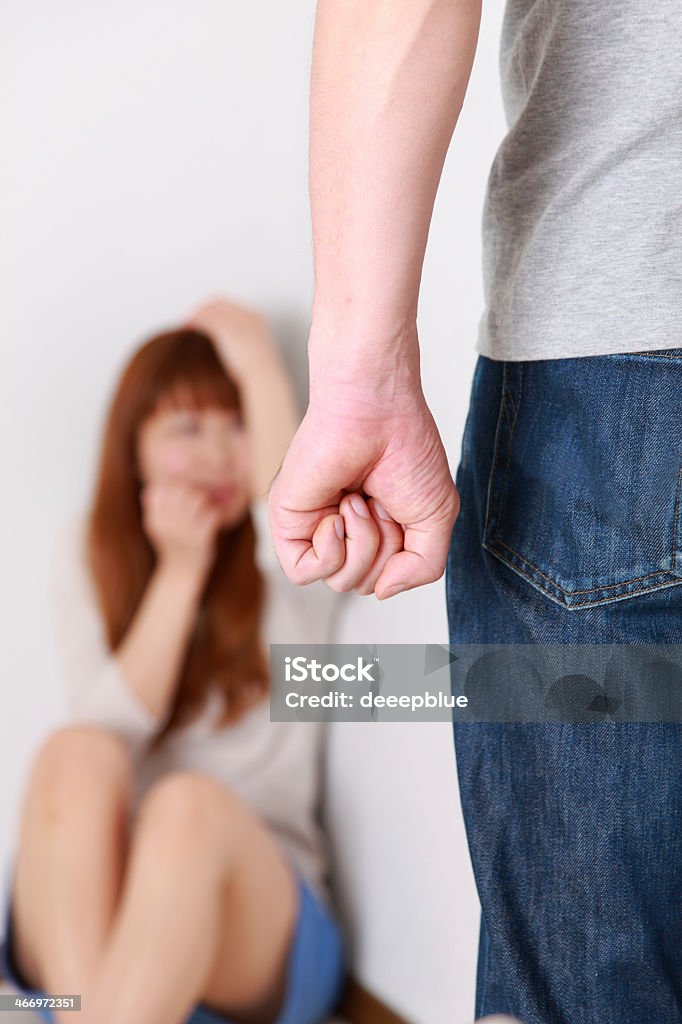 Man with clenched fist walks towards woman a man going to assault the woman. Domestic Violence Stock Photo