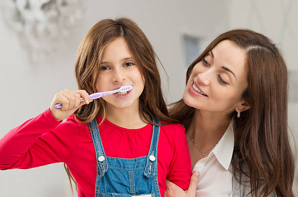 istock Girl With Her Mother Brushing Teeth 466972373
