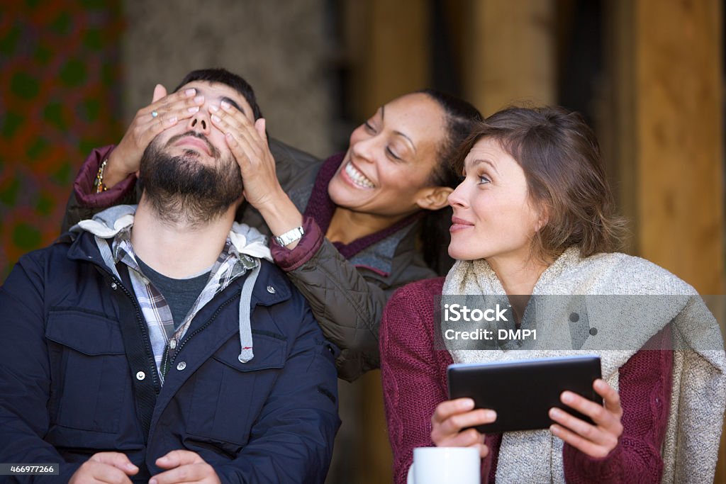 Woman surprising her friends upon arrival at an outdoor cafe A female friend surprising her friends upon arrival at an outdoor cafe. Arrival Stock Photo