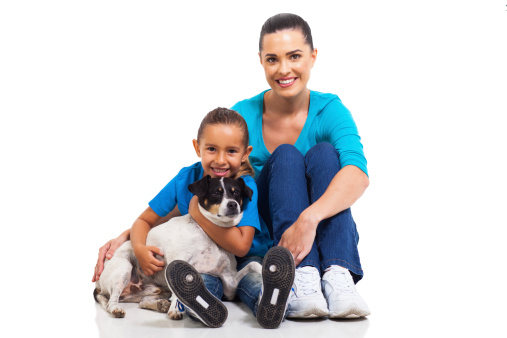 portrait of joyful mother sitting with her little daughter and pet dog on white background
