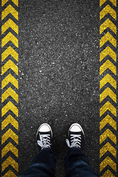 istock Converse-clad feet on asphalt with yellow lines on each side 466988276