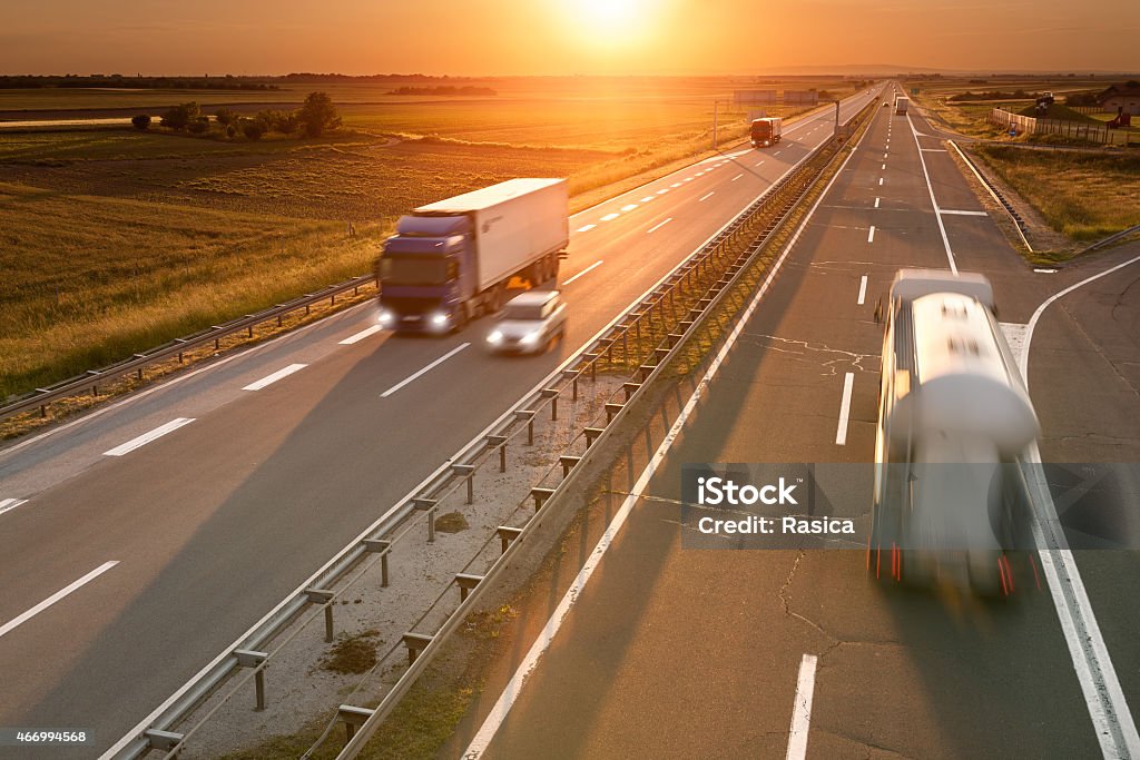 Trucks and car on the highway at sunset Trucks and car in motion blur on the freeway towards the setting sun. Rush hour on the motorway near Belgrade - Serbia. 2015 Stock Photo
