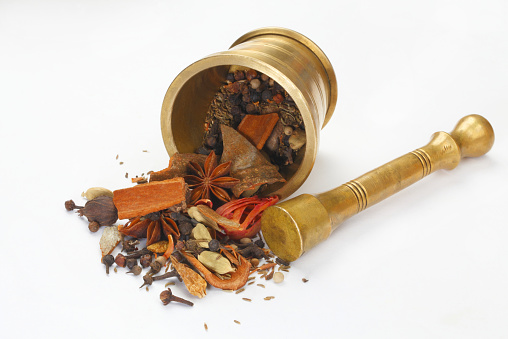 Variety of raw Authentic Indian Spices in an antique brass mortar isolated on white background (full frame).