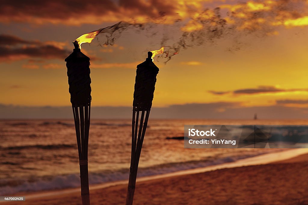 Tiki Lamps on the Beach of Hawaii Subject: Tiki torch lamp in a Hawaiian vacation resort against the sunset on a beach. Beach Stock Photo